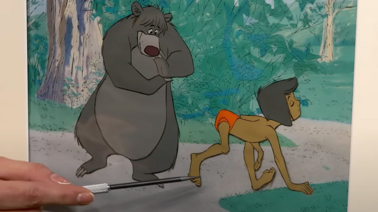 Die Filmzelle zeigt eine ikonische Szene: Mogli macht den Elefantengang vor Balu. 