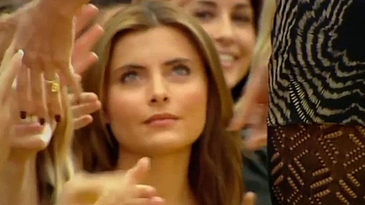 Sophia Thomalla steht an der Seite des Laufstegs und blickt zu Heidi Klum auf.